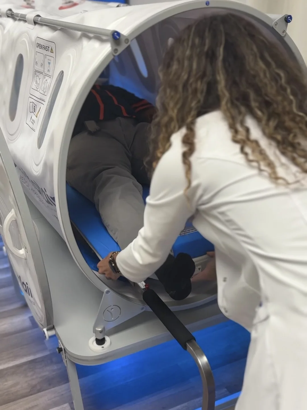 Team member helping a patient into the hyperbaric chamber at Bambu Recovery
